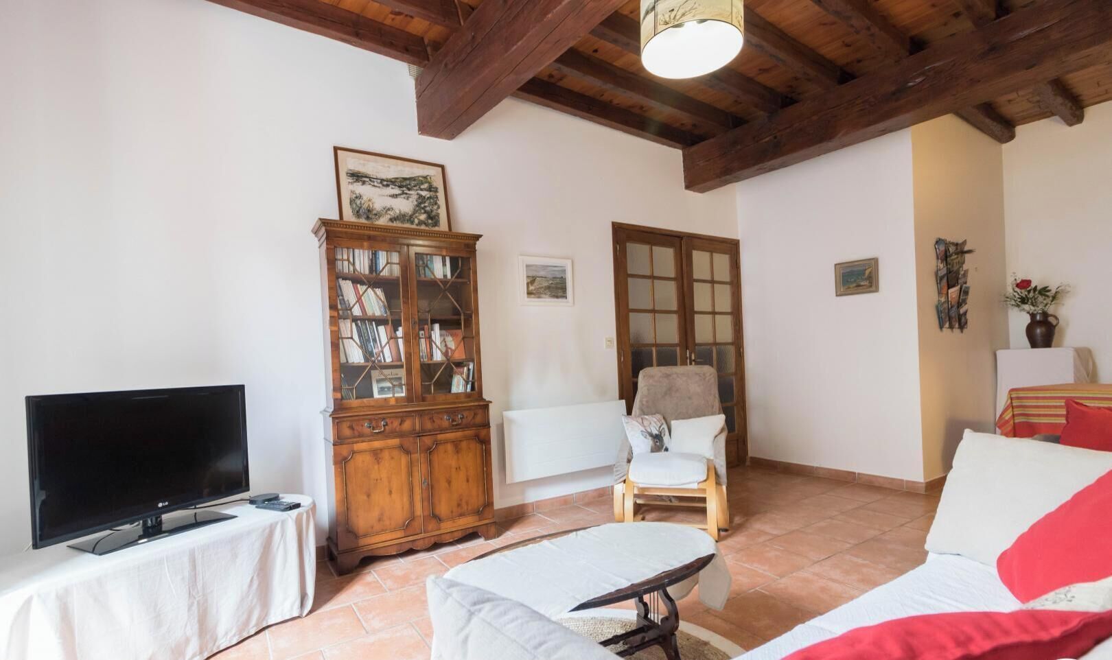 Saló amb televisor, armari de fusta, cadira i llit.