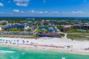 Luftaufnahme einer Küstenstadt mit Strand, Gebäuden und blauem Himmel.