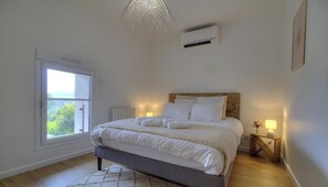 Une chambre à coucher avec un lit, des lampes de chevet, une fenêtre et un appareil de climatisation.