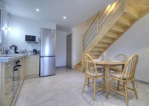 A modern kitchen with a built-in refrigerator, wooden dining table, and chairs.
