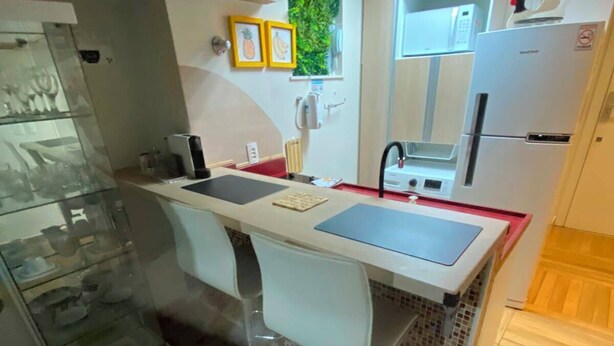 A compact kitchen with a central island, a refrigerator, and a microwave. - Studio Copa Beach (Rio de Janeiro)