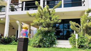 Un edificio con una struttura su due piani, un'area d'ingresso coperta e una statua di una figura su un piedistallo.
