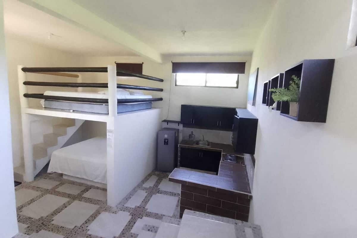 A compact room with bunk beds, a kitchenette, and a small window.