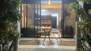 A patio area with a table and chairs, a clock, and potted plants.