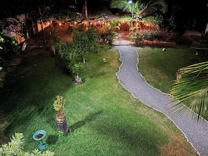 Un jardín cuidado con un sendero pavimentado, plantas en macetas y una pequeña fuente.