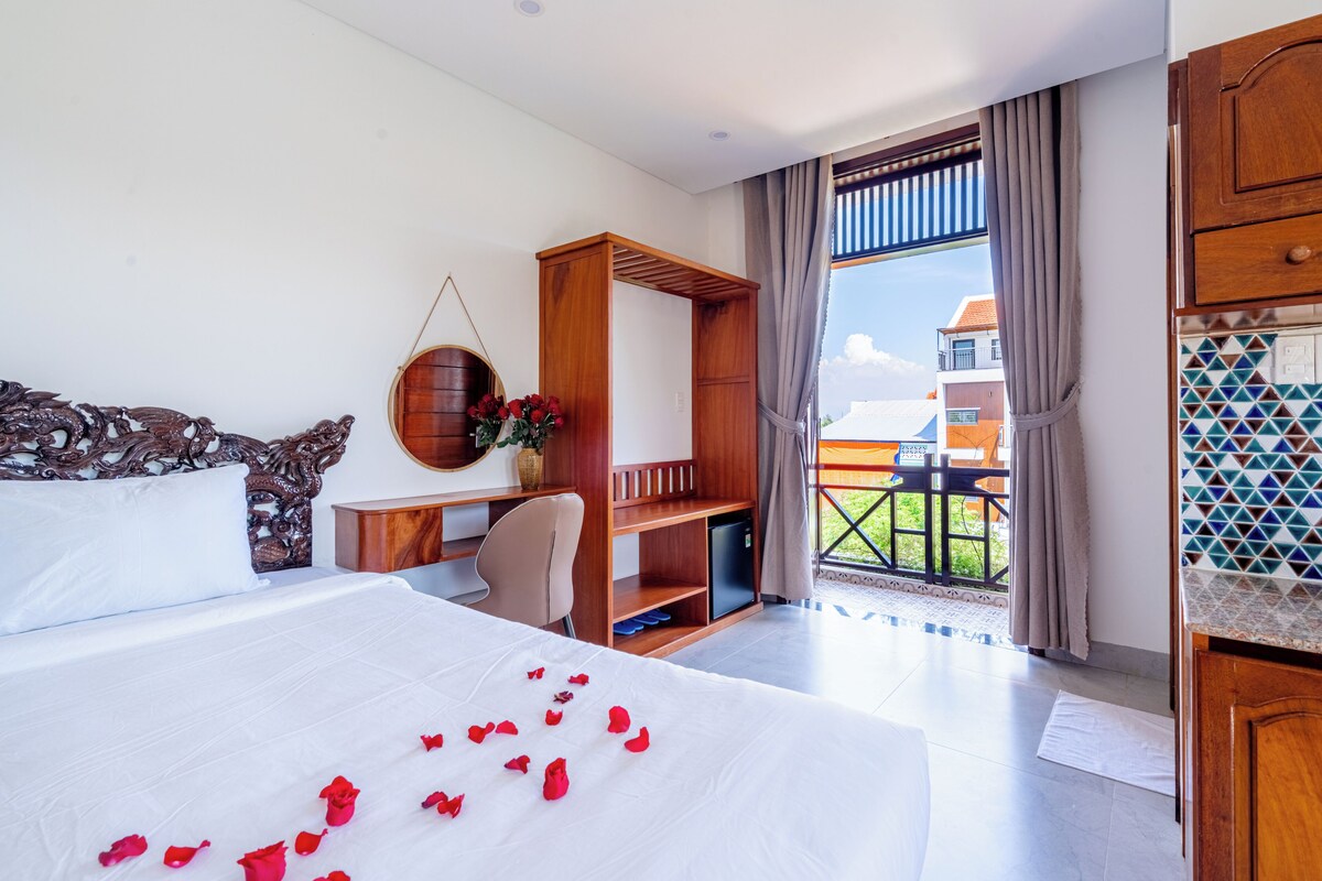 Une chambre d’hôtel avec un lit, un bureau, une chaise, une petite télévision et un balcon avec vue.
