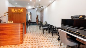 Eine Rezeption mit Beschilderung, ein Klavier und eine Sitzecke in der Hotelhalle.