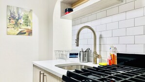 A modern kitchen with a stainless steel sink, a gas stove, and a wooden cabinet. - THE BEST WEST VILLAGE APARTMENT (New York)