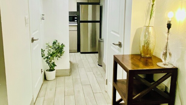 A narrow hallway with white walls, a wooden table with a vase and candle, and a kitchen in the background. - THE BEST WEST VILLAGE APARTMENT (New York)