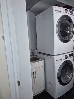 A compact laundry area with two stacked washing machines and a small sink.