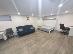 A room with a blue sofa, a bed, a desk, and a chair.