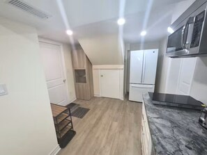 A kitchen with a marble countertop, a microwave, and a refrigerator.