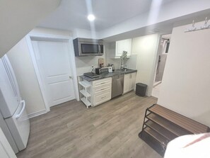 A compact kitchen with white cabinets, a microwave, a sink, and a small countertop.
