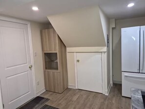 A kitchen with white cabinets, a built-in wooden cabinet, a white refrigerator, and a wooden floor.