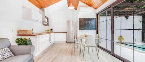 Una cocina moderna con comedor, techo de madera y ventanas amplias.
