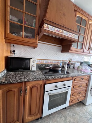 A kitchen with wooden cabinets, a microwave, a stove, and a dishwasher. - Apartment Sleeps 7 with Balcony (Velez-Malaga)