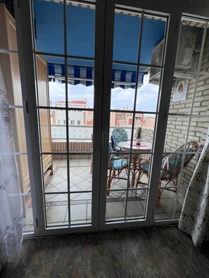 A room with a sliding glass door leading to an outdoor patio with a table and chairs. - Apartment Sleeps 7 with Balcony (Velez-Malaga)