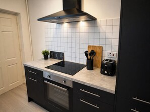 Une cuisine moderne avec un fourneau noir, un grille-pain et une planche à découper en bois.