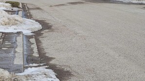 Uma passagem pavimentada ao lado de um muro de pedra com neve acumulada.