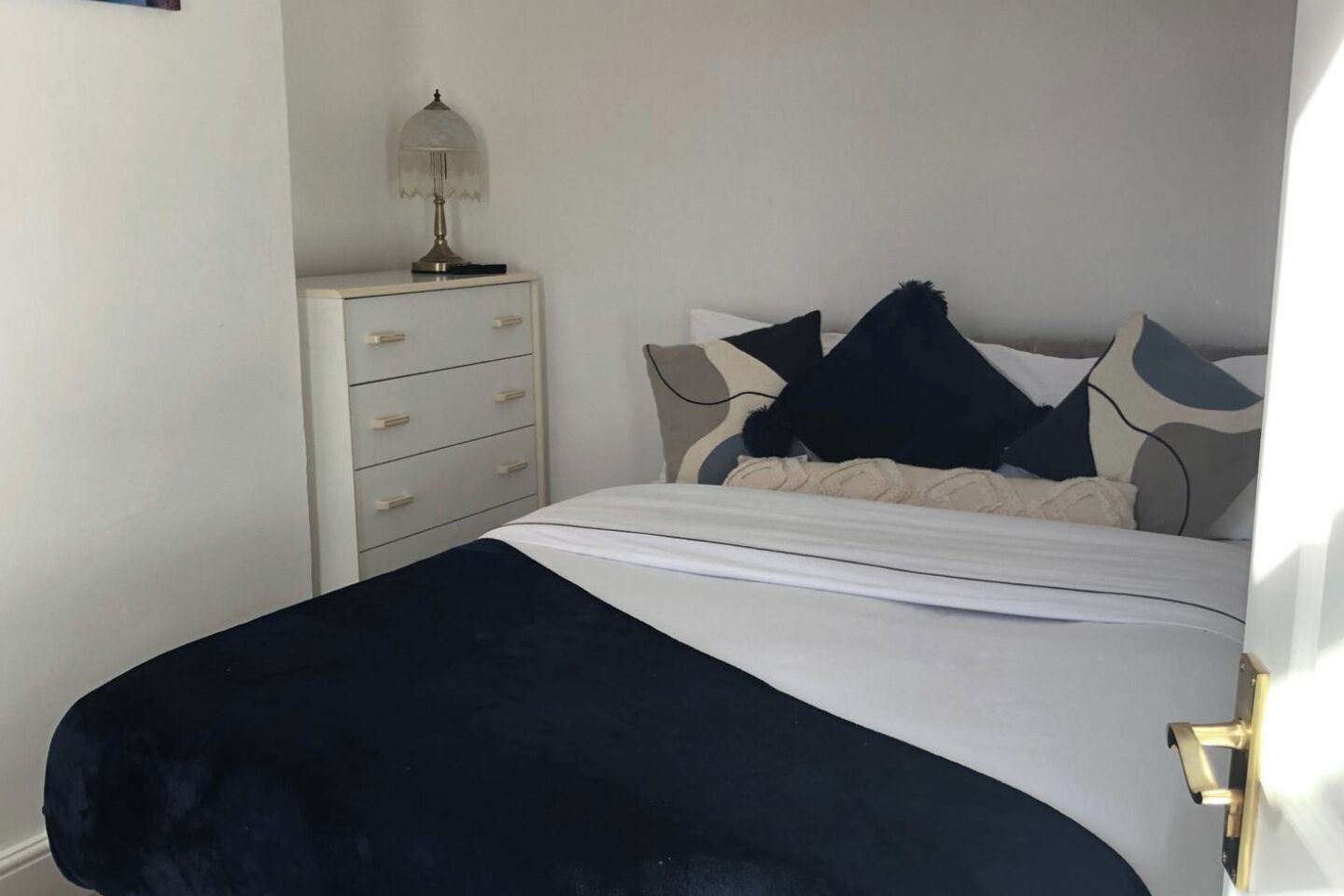 Une chambre à coucher avec un lit, une table de chevet avec une lampe et une commode.