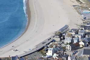 Une ville côtière dotée d’une longue jetée qui s’avance dans la mer, de bâtiments le long de la côte et d’une plage de sable.
