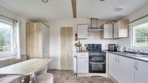 A compact kitchen with a dining area, a built-in oven, and a window providing a view of the outdoors.