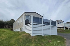 A mobile home with a fenced deck, a window, and a small porch.