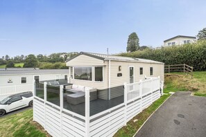 A mobile home with a balcony and a car parked in front. - Ty dee seaview escapes (Looe)