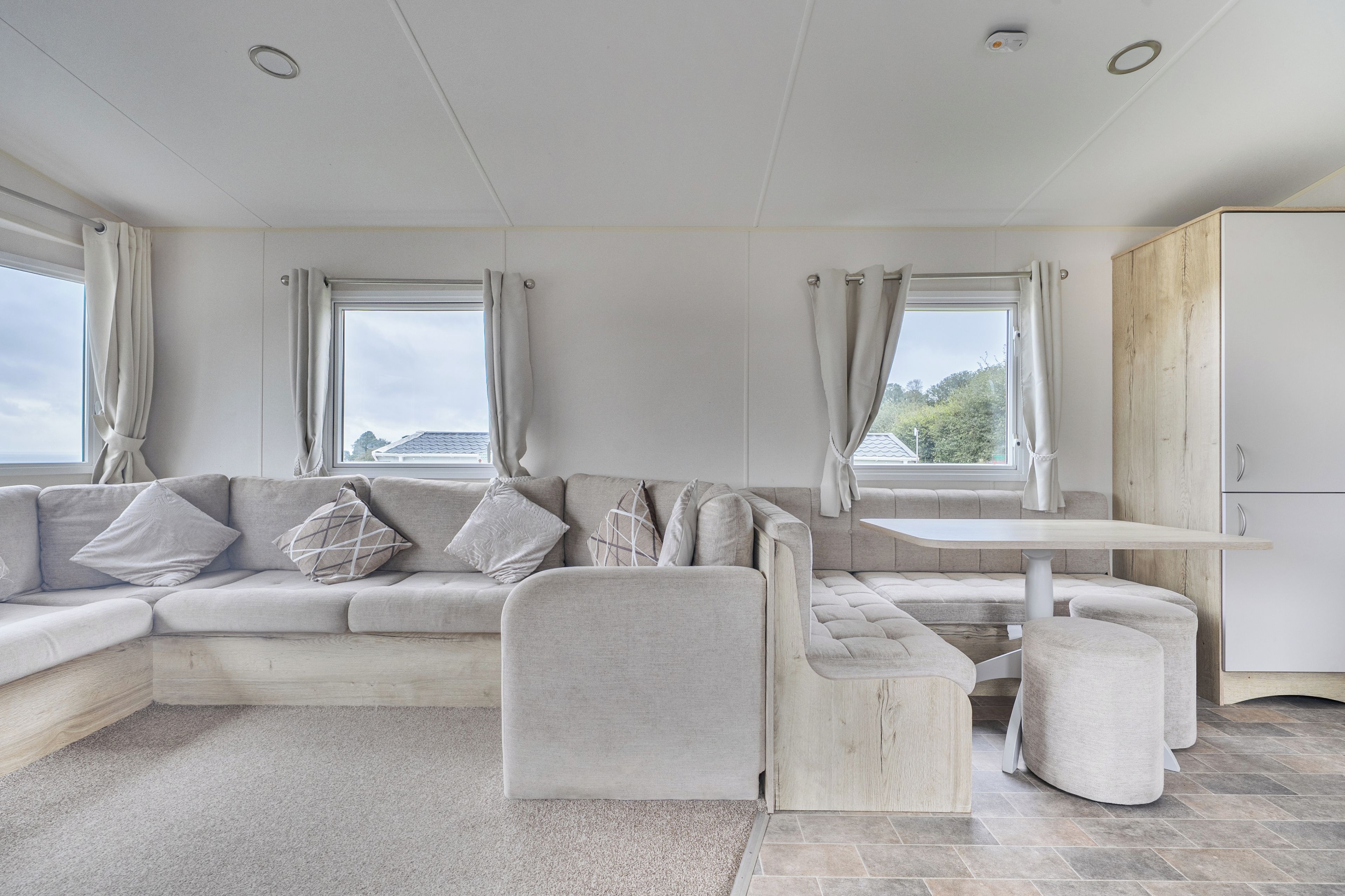 A modern living room with a sectional sofa, a small table, and a view of the outdoors.