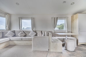 A modern living room with a sectional sofa, a small table, and a view of the outdoors.