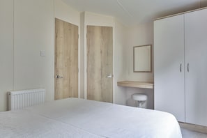 A bedroom with a bed, a wardrobe, a mirror, and a radiator.