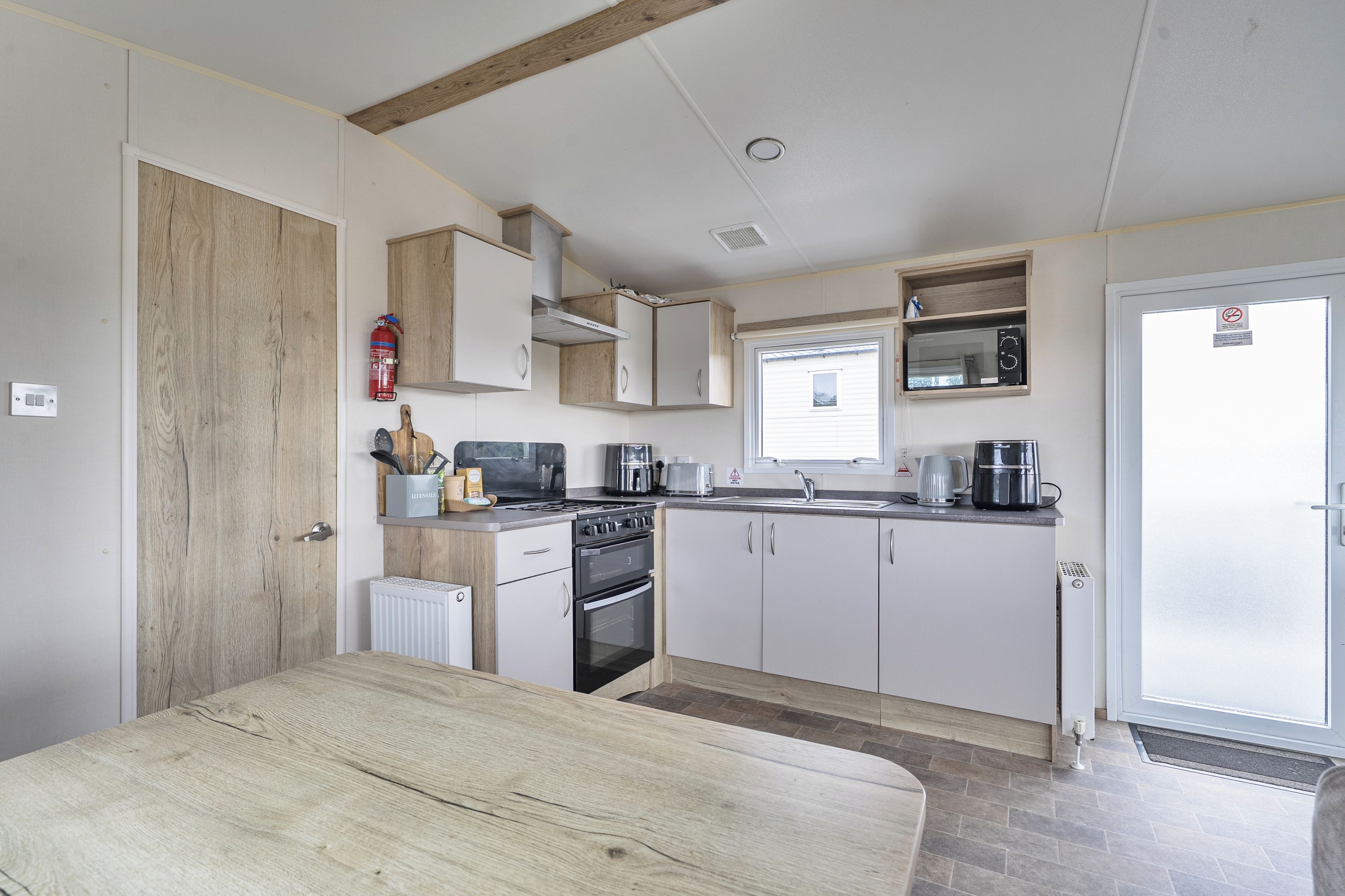 A compact kitchen with white cabinets, a stove, a microwave, and a coffee maker.