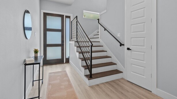 Un escalier avec une rampe noire, une porte blanche et une petite fenêtre au-dessus de la porte.