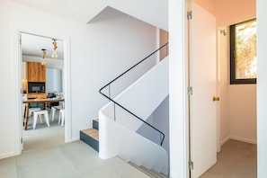 A modern interior with a spiral staircase, a kitchen area, and a dining space.