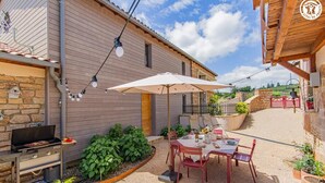 A patio with a grill, outdoor seating, and a view of the countryside. - Le Tinailler - PRISSE (PRISSE)