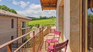 A balcony with red chairs, a wooden deck, and a view of vineyards. - Le Tinailler - PRISSE (PRISSE)