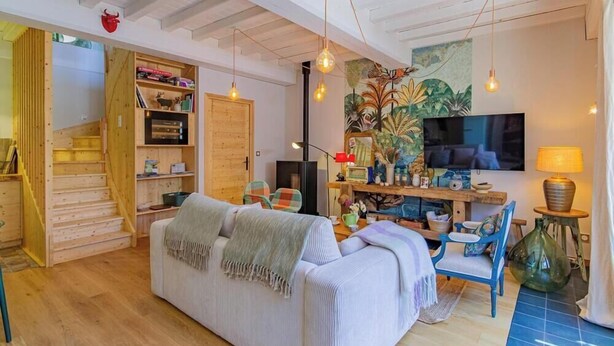 A cozy living room with a sofa, a wooden staircase, a TV, and a bookshelf. - Le Tinailler - PRISSE (PRISSE)