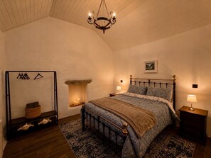 A bedroom with a bed, a hanging light fixture, a fireplace, and a wooden floor. - Cottage Sleeps 4 with Parking (Killarney)