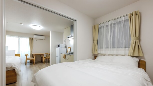 A hotel room with a bed, a desk, a chair, a kitchenette, and a bathroom. - Kasatori-cho I [9-minute drive from Nagoya Station] Newly Built 1LDK / WiFi Included / Full Amenities / Sleeps Up to 3 / Ideal for Sightseeing / 1-101 (Kasatori-cho, Nishi-ku, Nagoya City,)