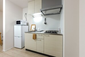 A compact kitchen with a microwave, stove, and a framed picture on the counter.