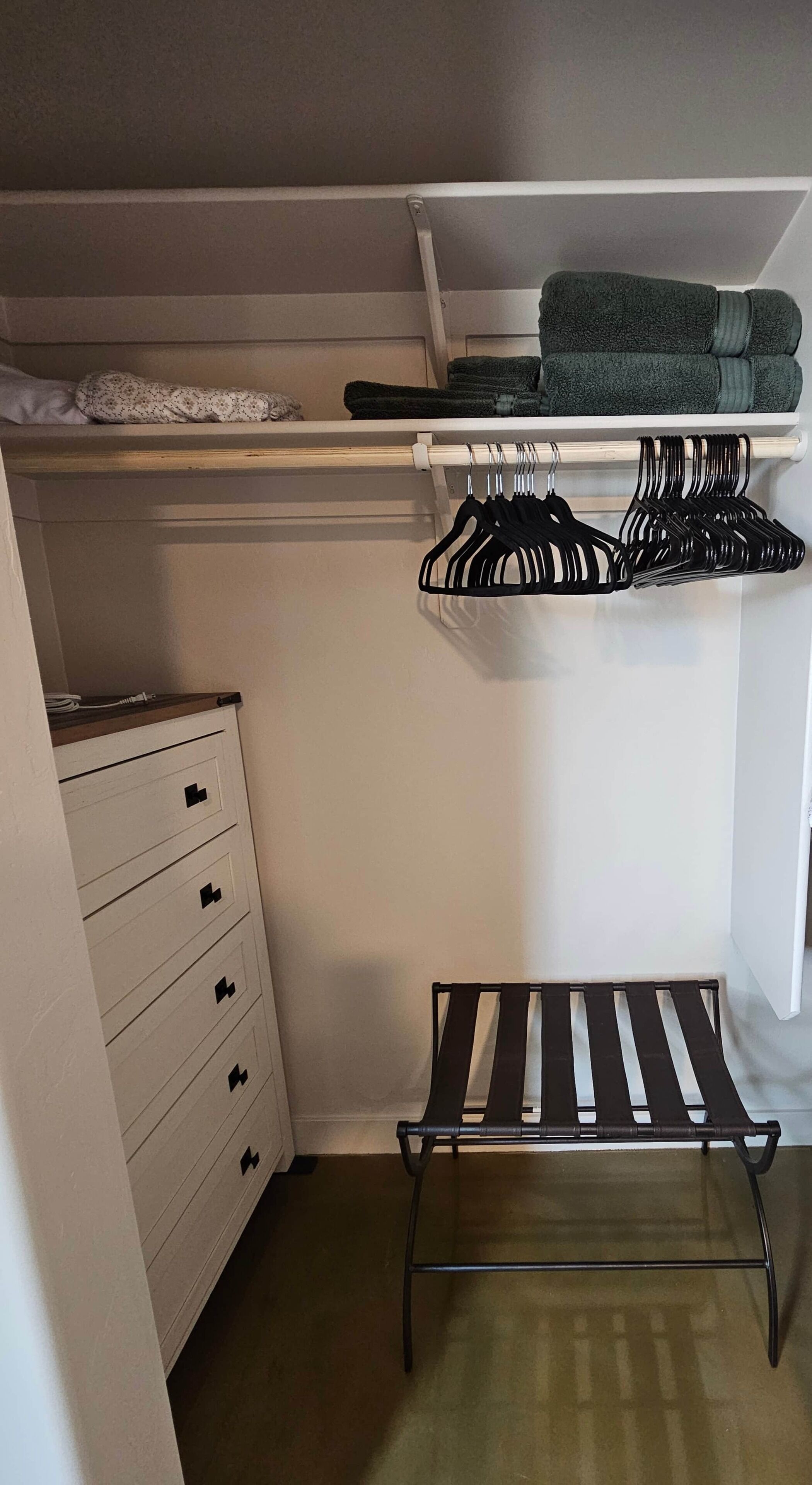 A closet with hanging space, a bench, and a set of drawers.