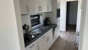 A modern kitchen with white cabinets, a stainless steel sink, and a built-in oven.