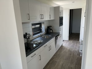 Een moderne keuken met witte kasten, een roestvrijstalen spoelbak en een inbouwoven.
