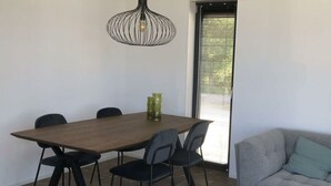 A dining area with a wooden table, black chairs, a hanging light fixture, and a window with blinds.