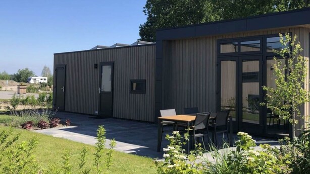 A modern building with a covered patio area, a door, and a window.