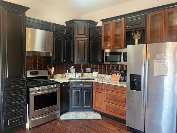 A kitchen with dark cabinetry, stainless steel appliances, and a wooden floor.
