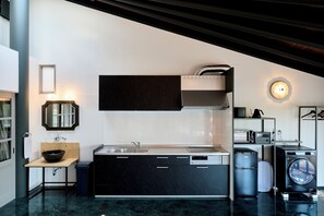 A modern kitchen with a sink, cabinets, a microwave, and a washing machine.