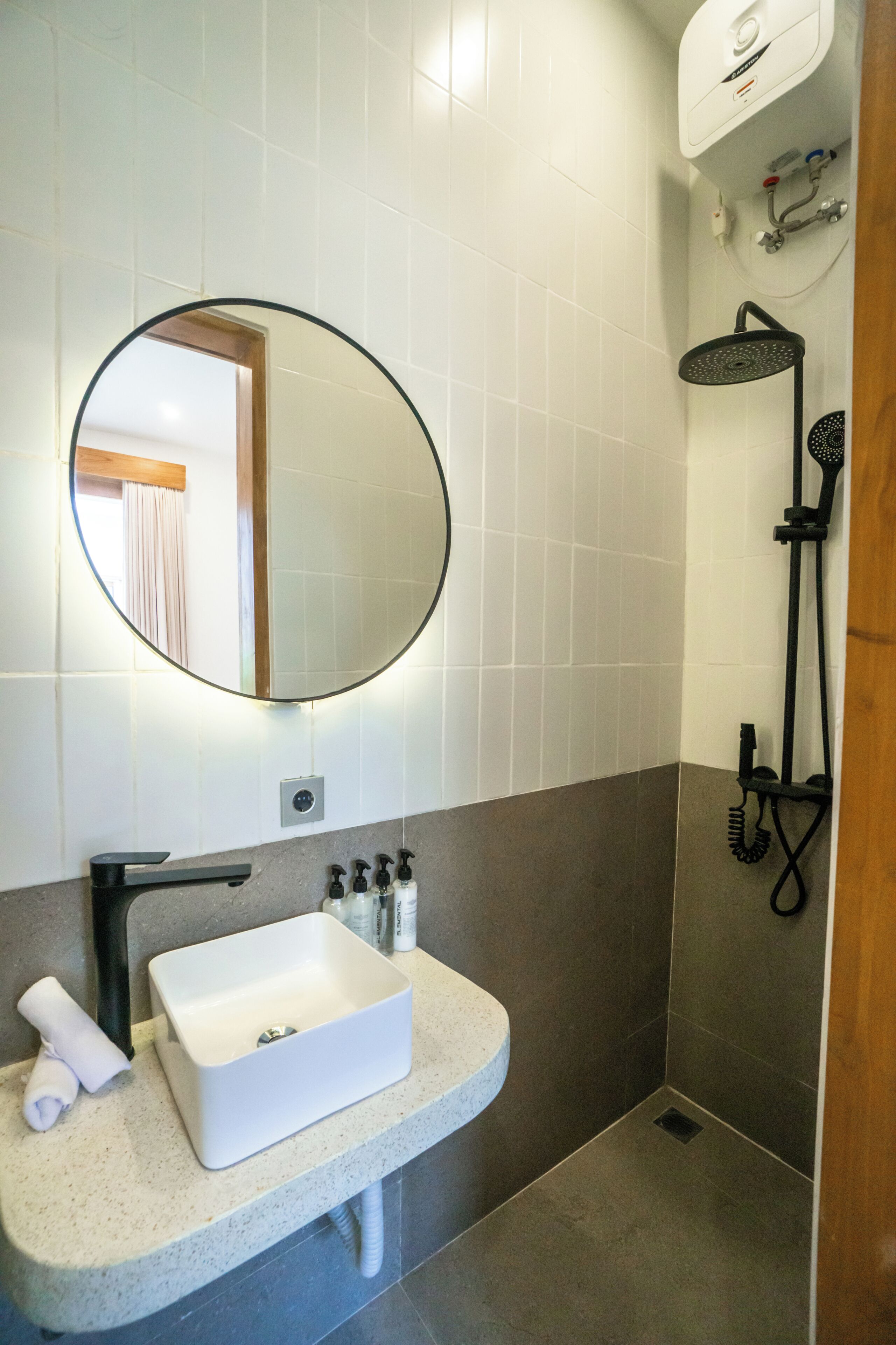 A bathroom with a white sink, a mirror, a shower, and a towel rack.