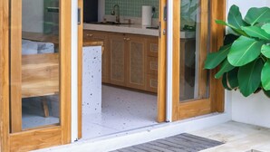 Een moderne keuken met houten kastjes, een hanglamp en uitzicht op de woonkamer.