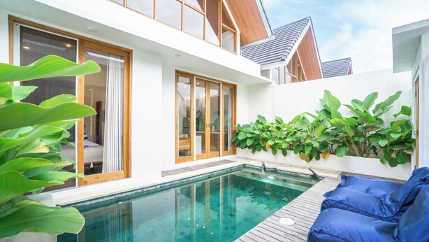 Een modern huis met een zwembad, houten terras en grote ramen.